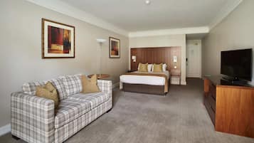 Una habitación de hotel con una cama, un sofá, un escritorio y un televisor.