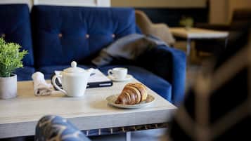 Ein gemütlicher Sitzbereich mit Tisch, einem Croissant, einer Tasse und einem Teekessel.