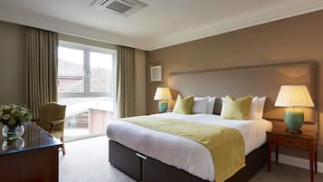 A hotel room with a large bed, two bedside lamps, a chair, a desk, and a window with curtains.