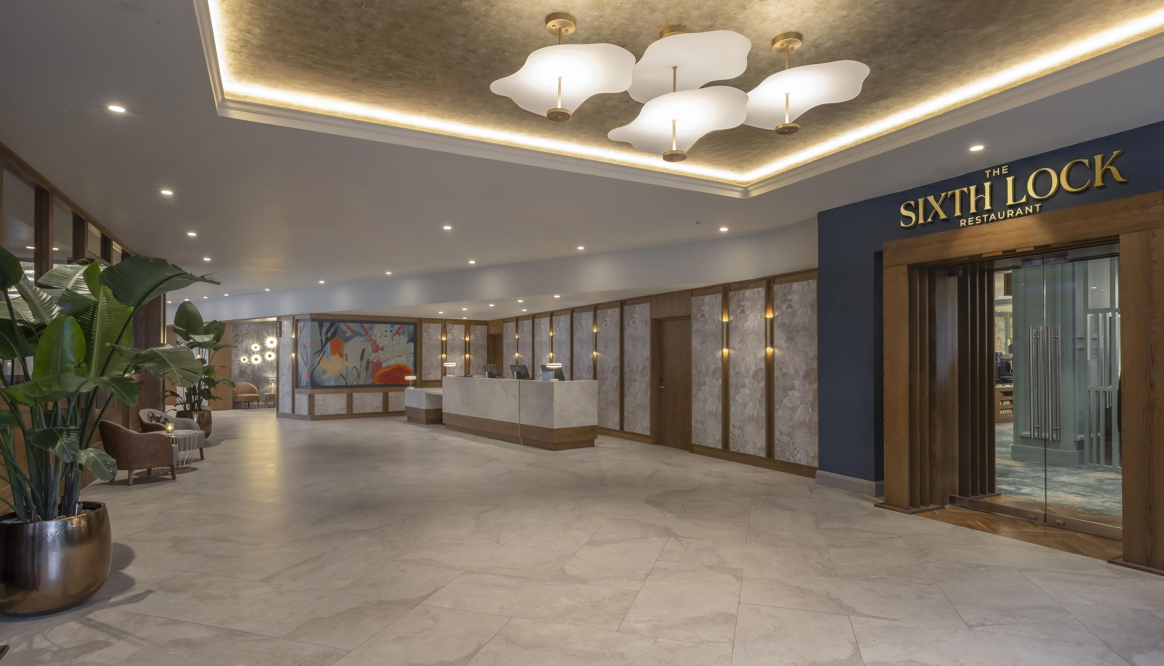 A hotel lobby with a reception desk, seating area, and a large window with a view.