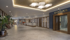 Un hall d’hôtel comprenant un comptoir d’accueil, un espace salon et une grande fenêtre offrant une vue panoramique.