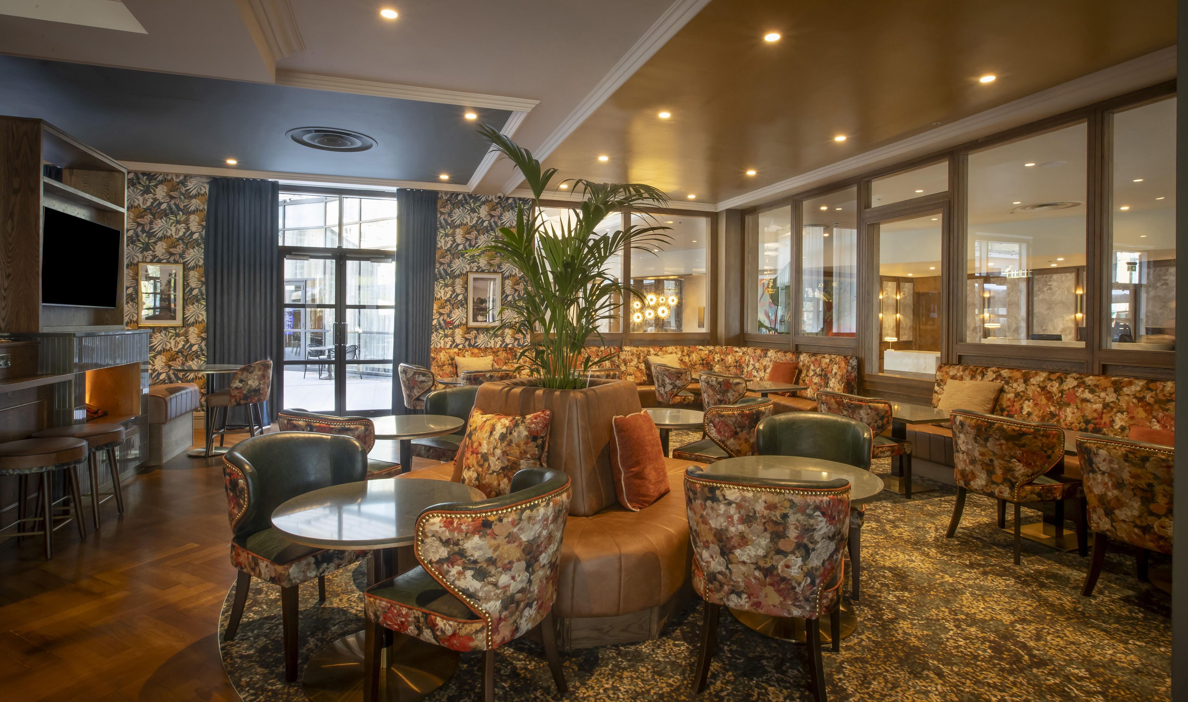 A hotel lobby with a seating area, a bar, and a television.