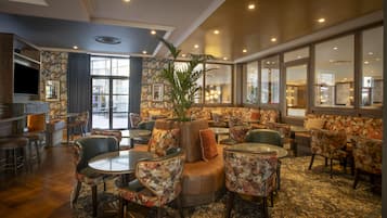 A hotel lobby with a seating area, a bar, and a television.