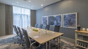 A conference room with a long table, chairs, a coffee machine, and artwork on the wall. - Hilton Dublin (Dublin)