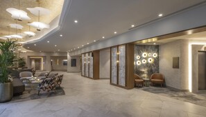 Un hall d’hôtel comprenant un espace salon, un comptoir d’accueil et un mur orné d’un luminaire circulaire.
