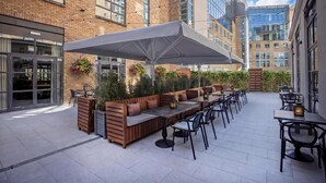 An outdoor patio with seating, tables, and string lights. - Hilton Dublin (Dublin)
