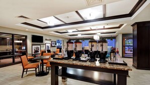 A modern hotel lobby with a central granite counter, seating area, and a large TV screen. - Comfort Inn & Suites Mt. Holly - Westampton (Mount Holly)