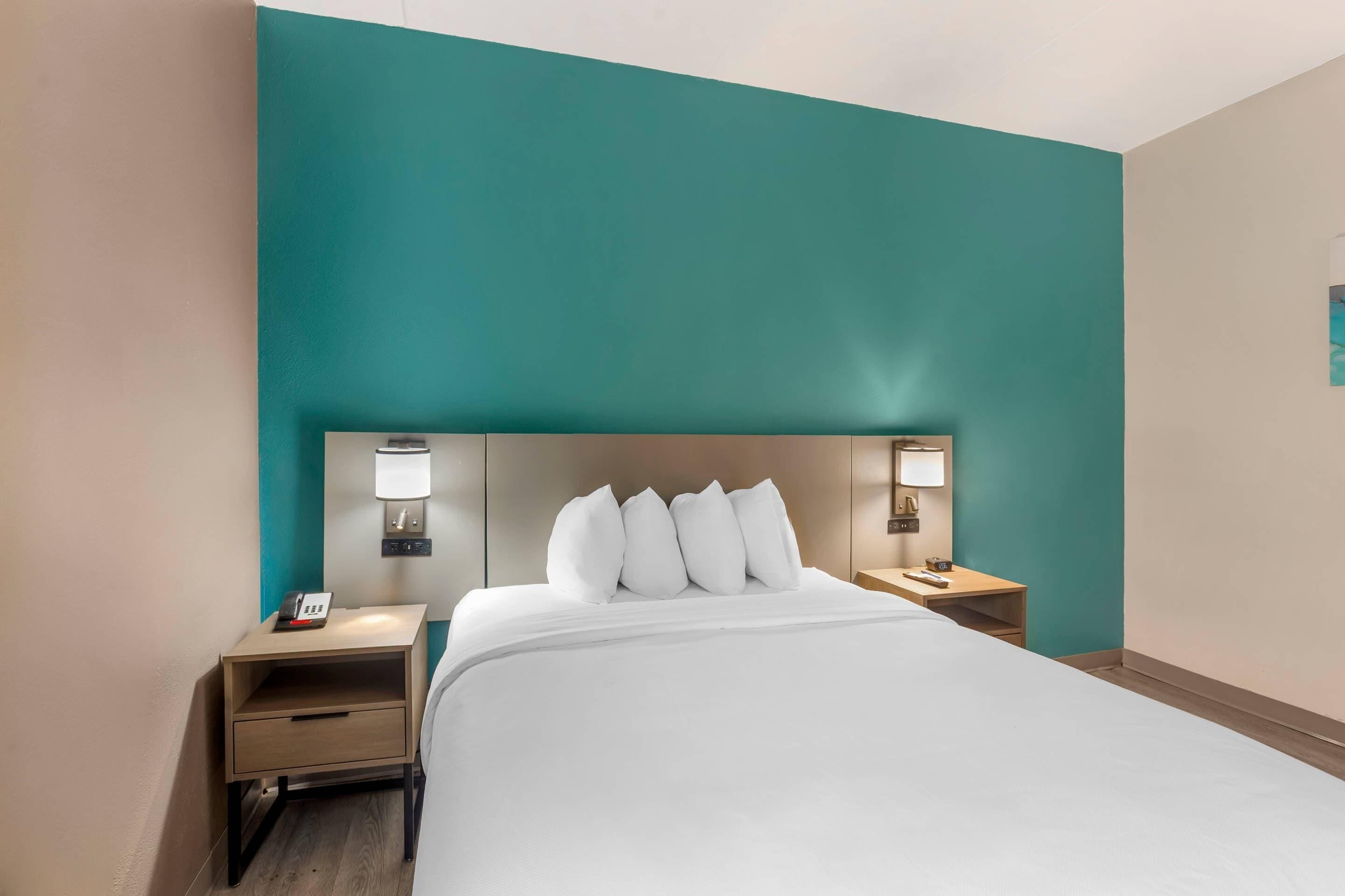 Ein Hotelzimmer mit einem großen Bett, zwei Nachttischen und Wänden in Türkis.