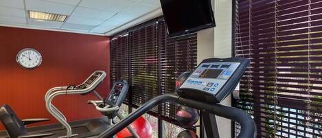 Un gimnasio con cintas de correr, una bicicleta estática y pelotas de ejercicio.