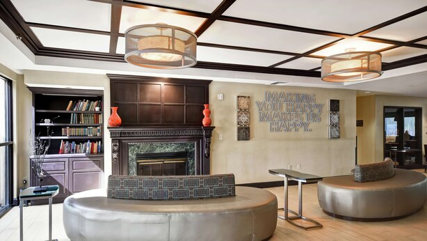 A modern living room with a fireplace, round seating, and a bookshelf. - Comfort Inn & Suites Mt. Holly - Westampton (Mount Holly)