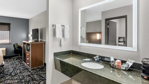 Ein Hotelbad mit großem Spiegel, Waschbecken, Schrank und Stuhl.