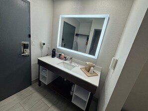 A bathroom with a white sink, a mirror, a towel rack, and a door.