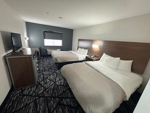 Une chambre d’hôtel avec deux lits, un bureau, une télévision et une fenêtre.