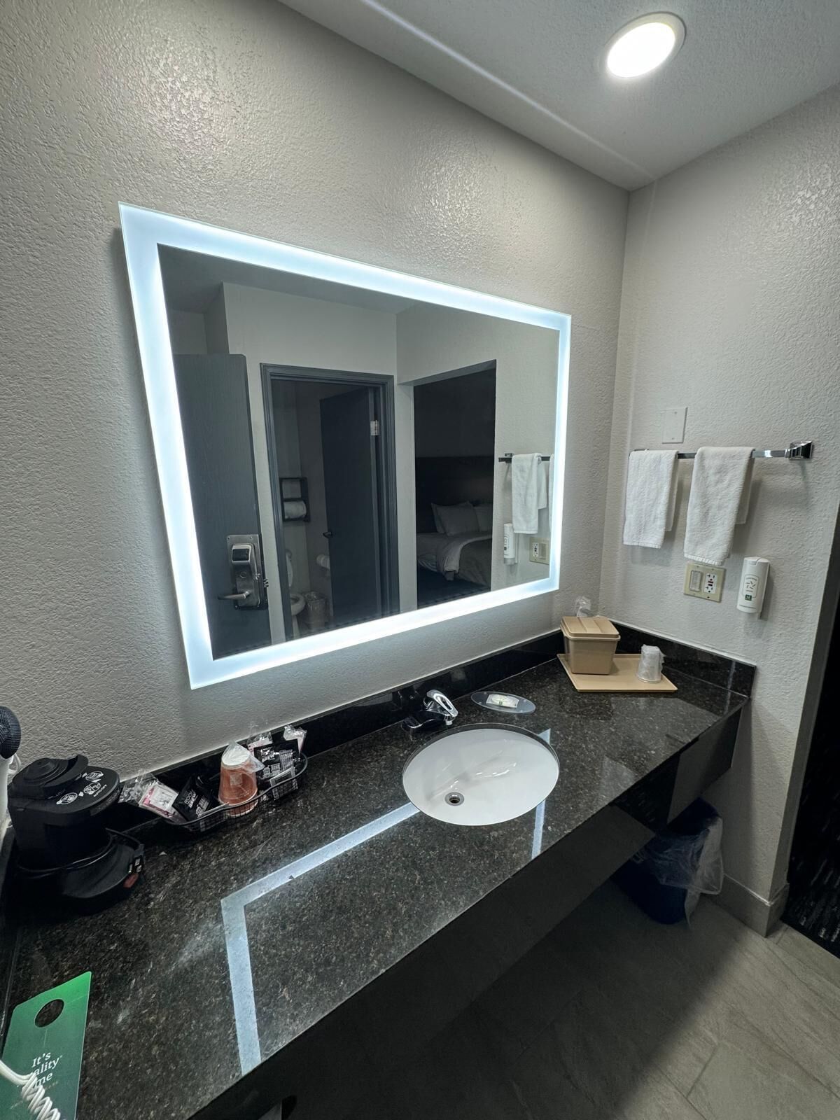 Une salle de bain moderne avec un grand miroir, un lavabo et un porte-serviettes.
