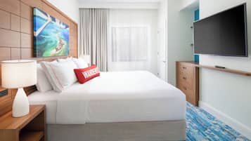 A hotel room with a large bed, a flat-screen TV, a painting on the wall, and a window with curtains.