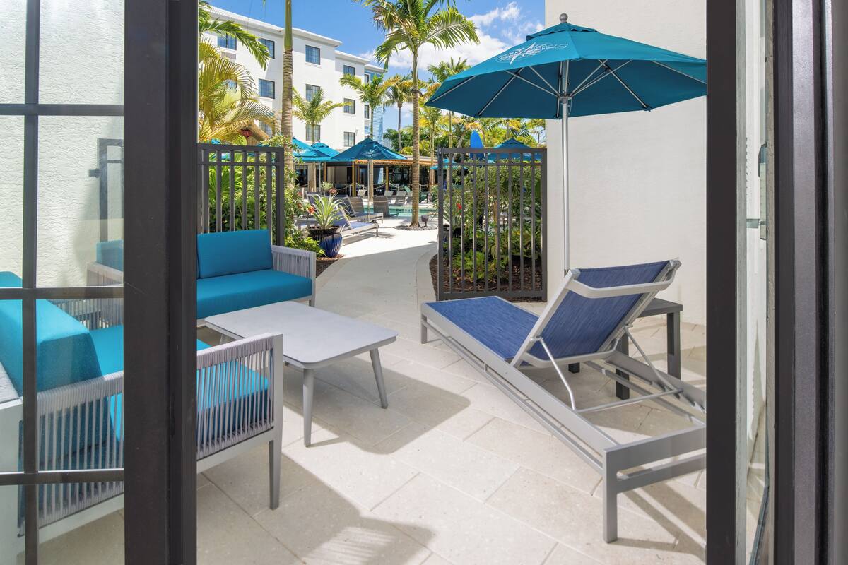 A sunlit outdoor patio with lounge chairs, a table, and umbrellas.