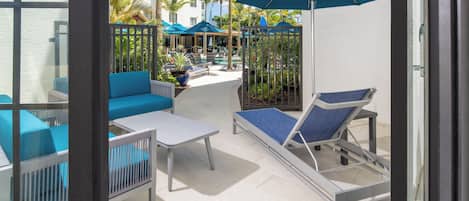 A sunlit outdoor patio with lounge chairs, a table, and umbrellas.