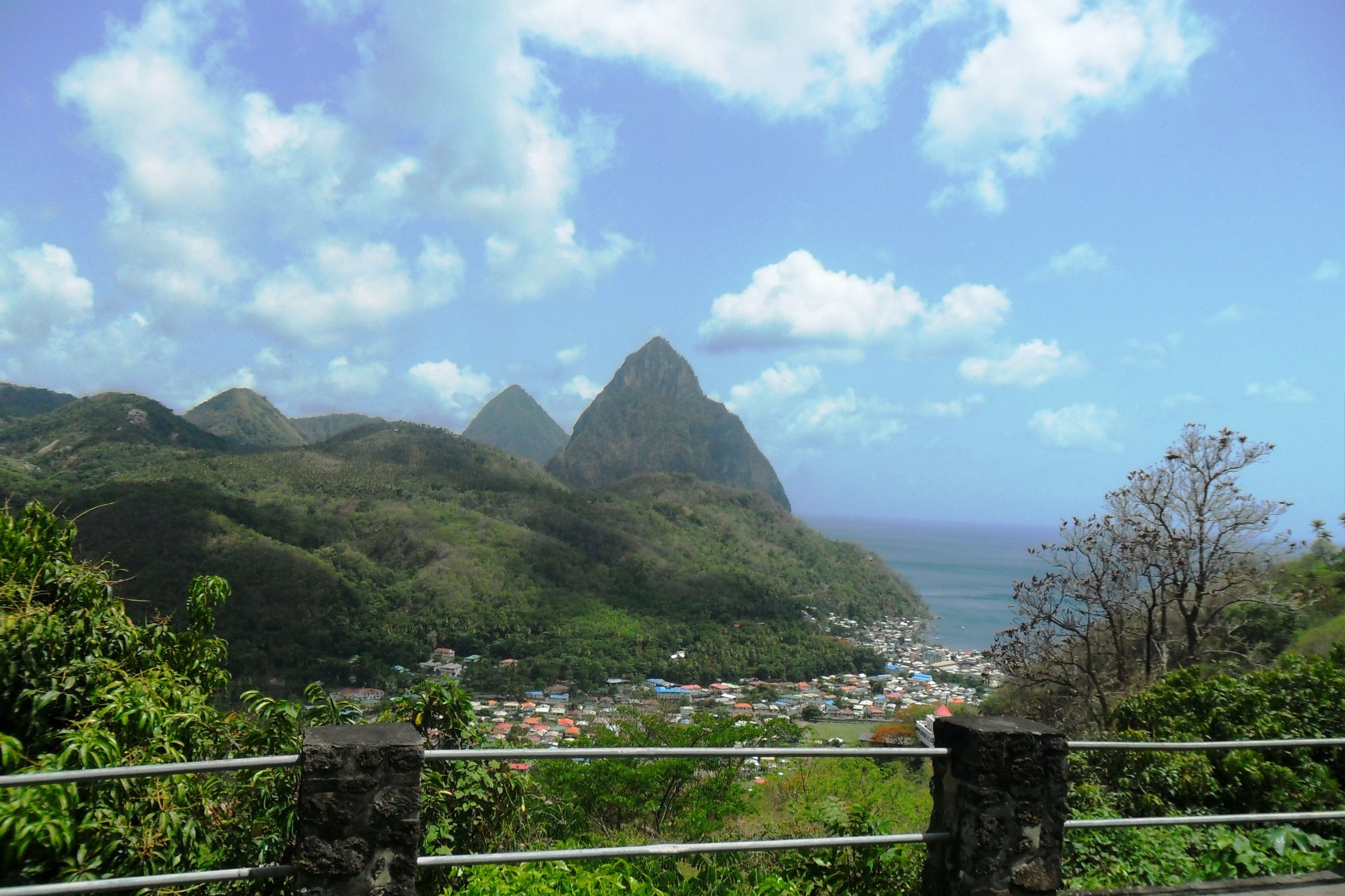 A coastal town with mountains in the background, a clear sky, and a view of the ocean.