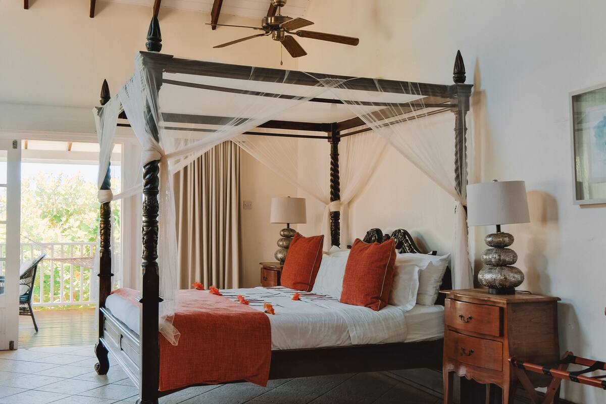 Una cama con dosel y cortinas, una mesita de noche con lámpara y una silla.