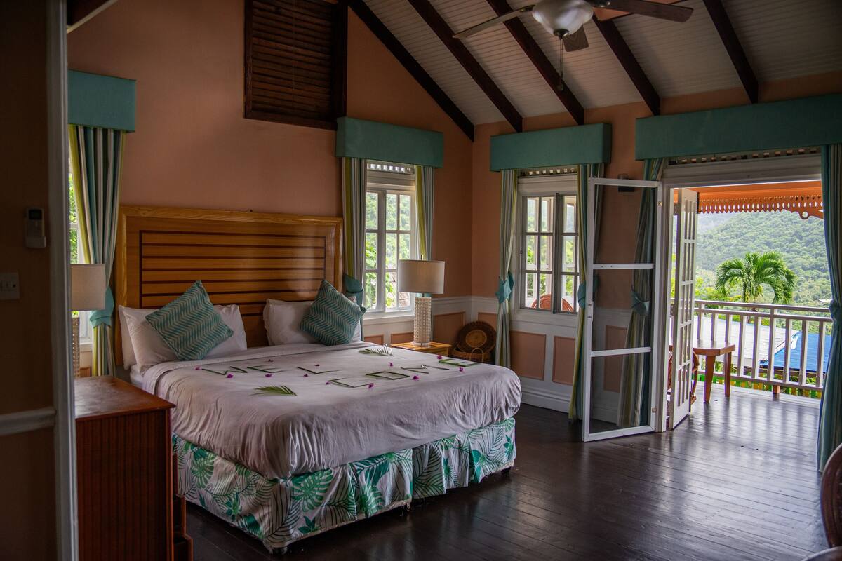 Un dormitorio con una cama grande, cabecera de madera y un balcón con vistas al exterior.