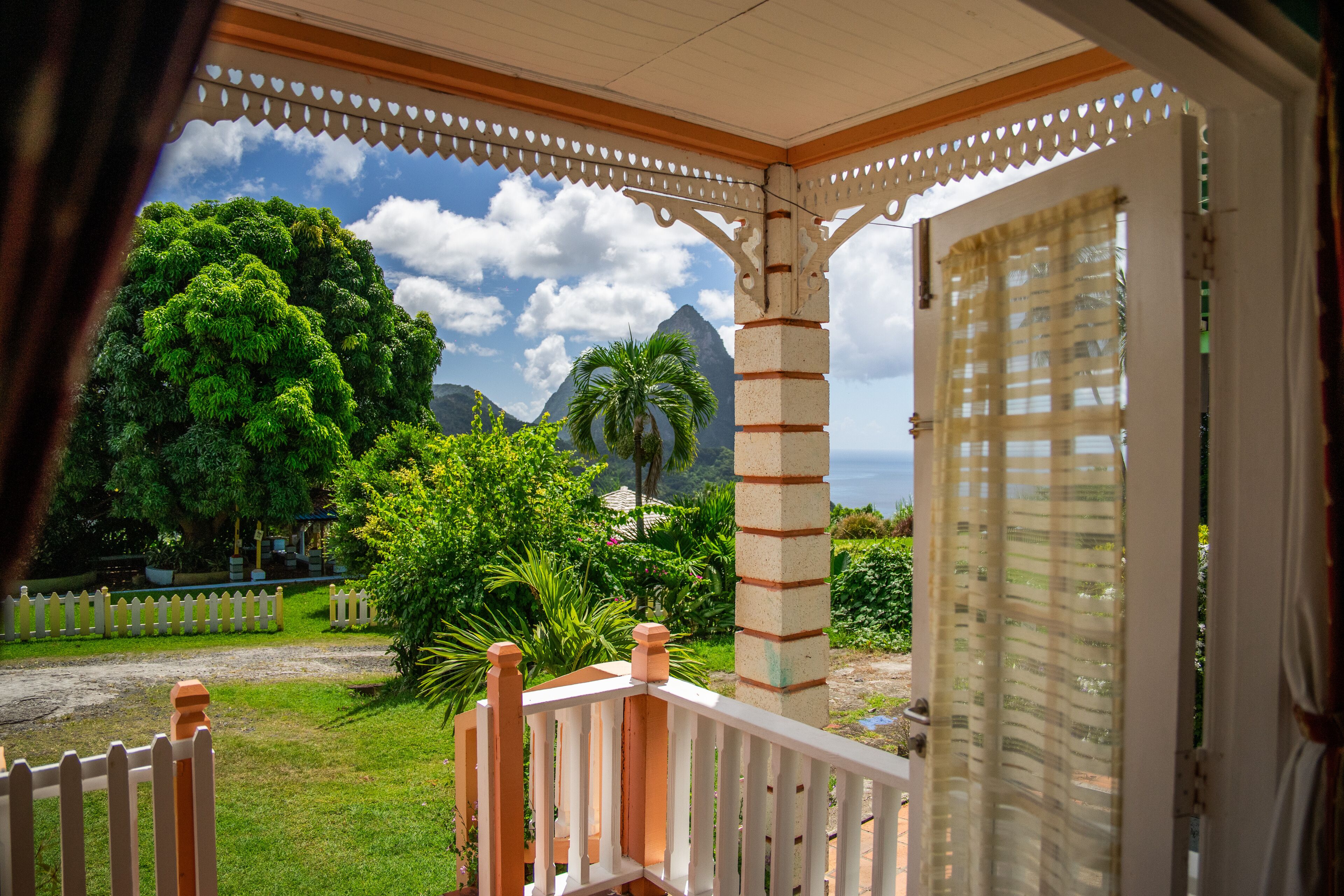 A covered porch with a view of lush greenery and mountains.