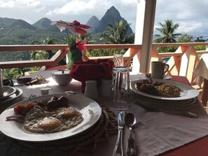 A dining table with plates of food, cutlery, and a vase of flowers. - La Haut Resort (Soufrière)