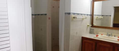 Et badeværelse med bruser, toilet, vask og træskabe.