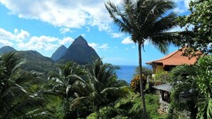 Un paisaje tropical con una montaña y un edificio de techo rojo.