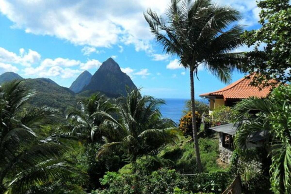 Un paisaje tropical con una montaña y un edificio de techo rojo.