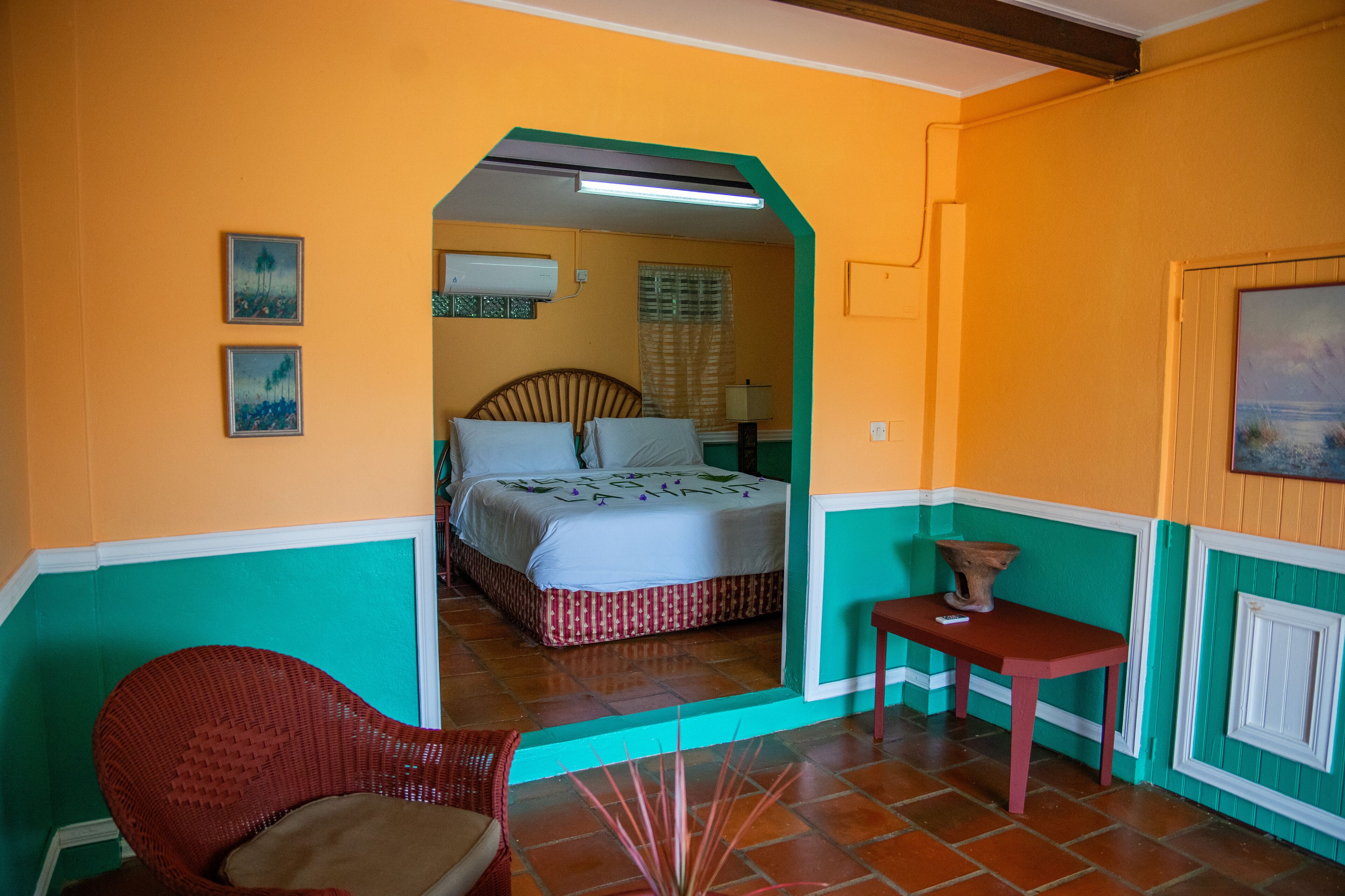 A room with a bed, a chair, a table, and a painting on the wall.
