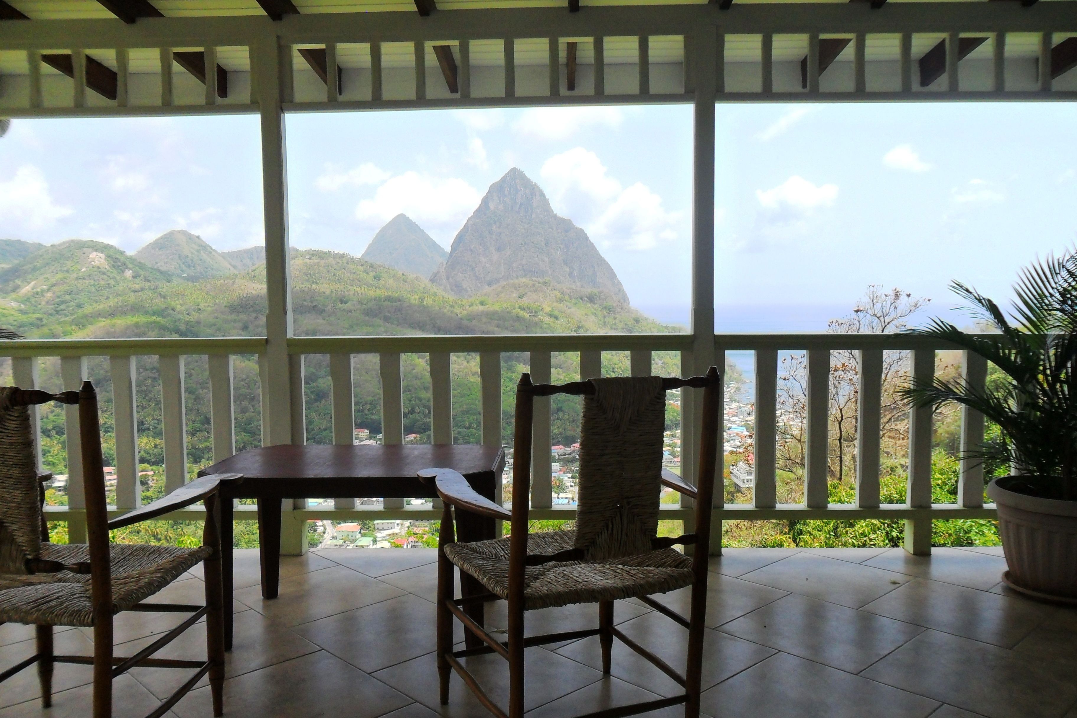 A balcony with a table and chairs, overlooking a mountainous landscape.