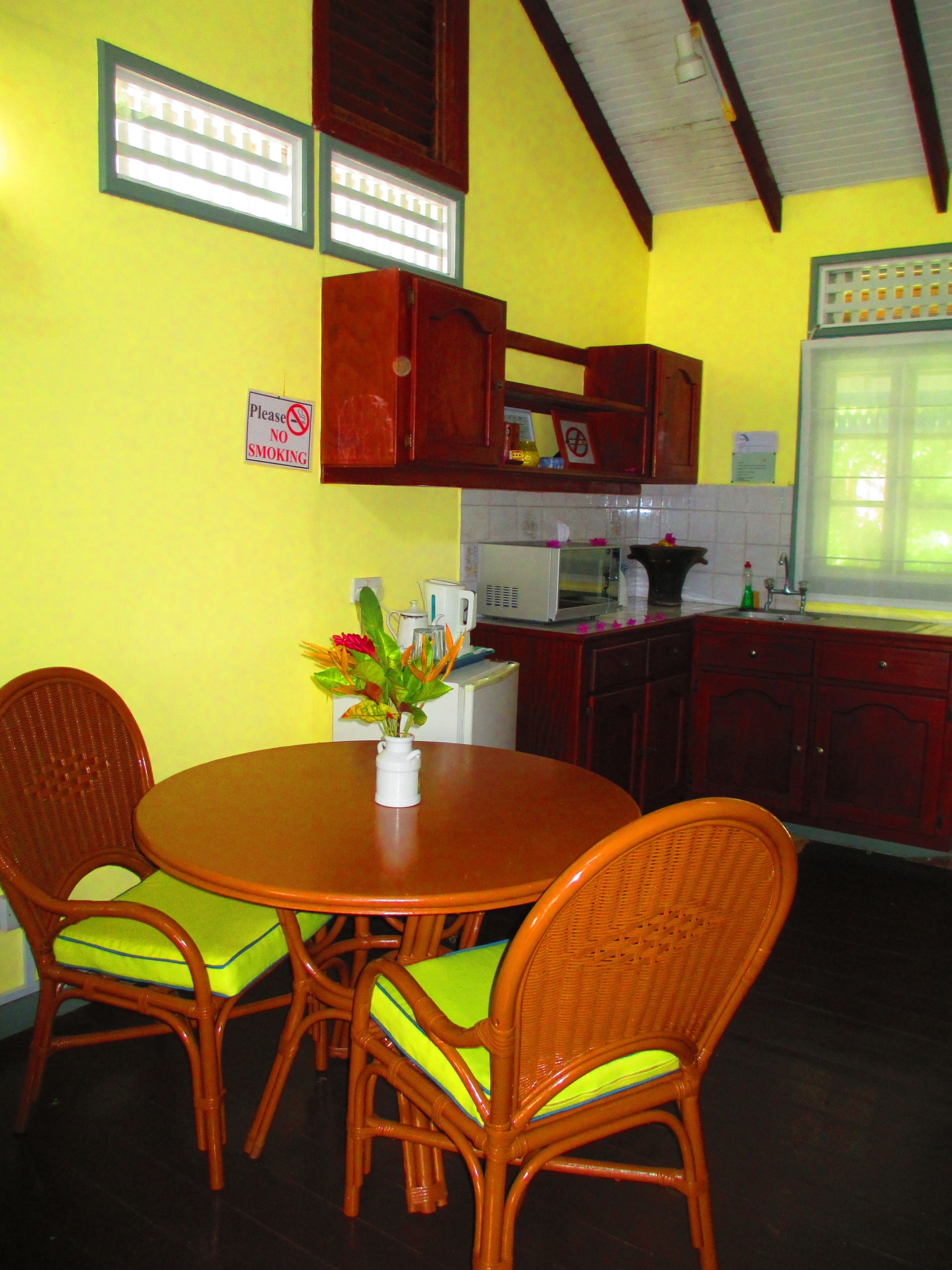 Una cocina con una mesa de comedor y sillas, un microondas y armarios.