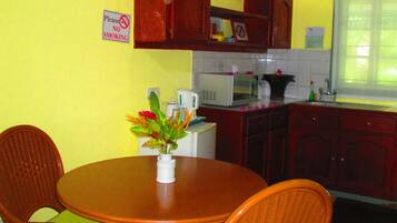 Una cocina con una mesa de comedor y sillas, un microondas y armarios.