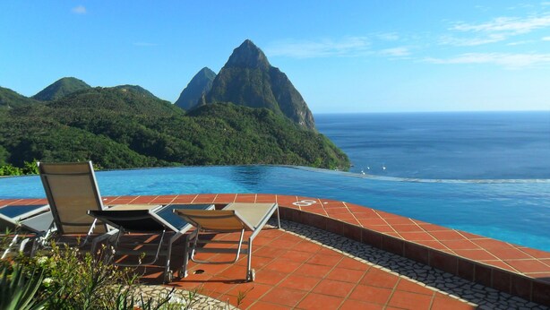 Una piscina infinita con vistas a una montaña y al océano.