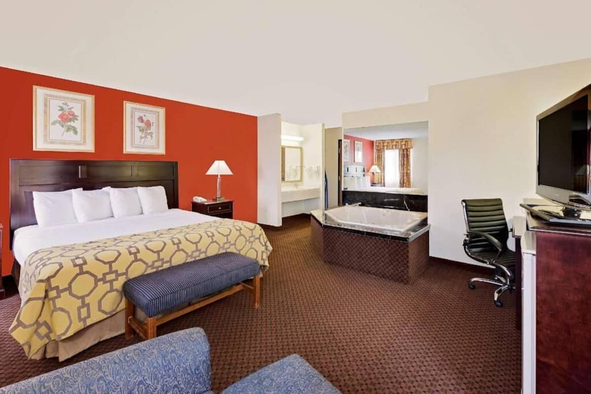 Ein Hotelzimmer mit einem Bett, einem Schreibtisch, einem Stuhl, einer Badewanne und einem Fernseher.
