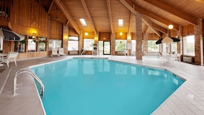 Ein beheizter Innenpool mit klarem Wasser, umgeben von Holzwänden und großen Fenstern.