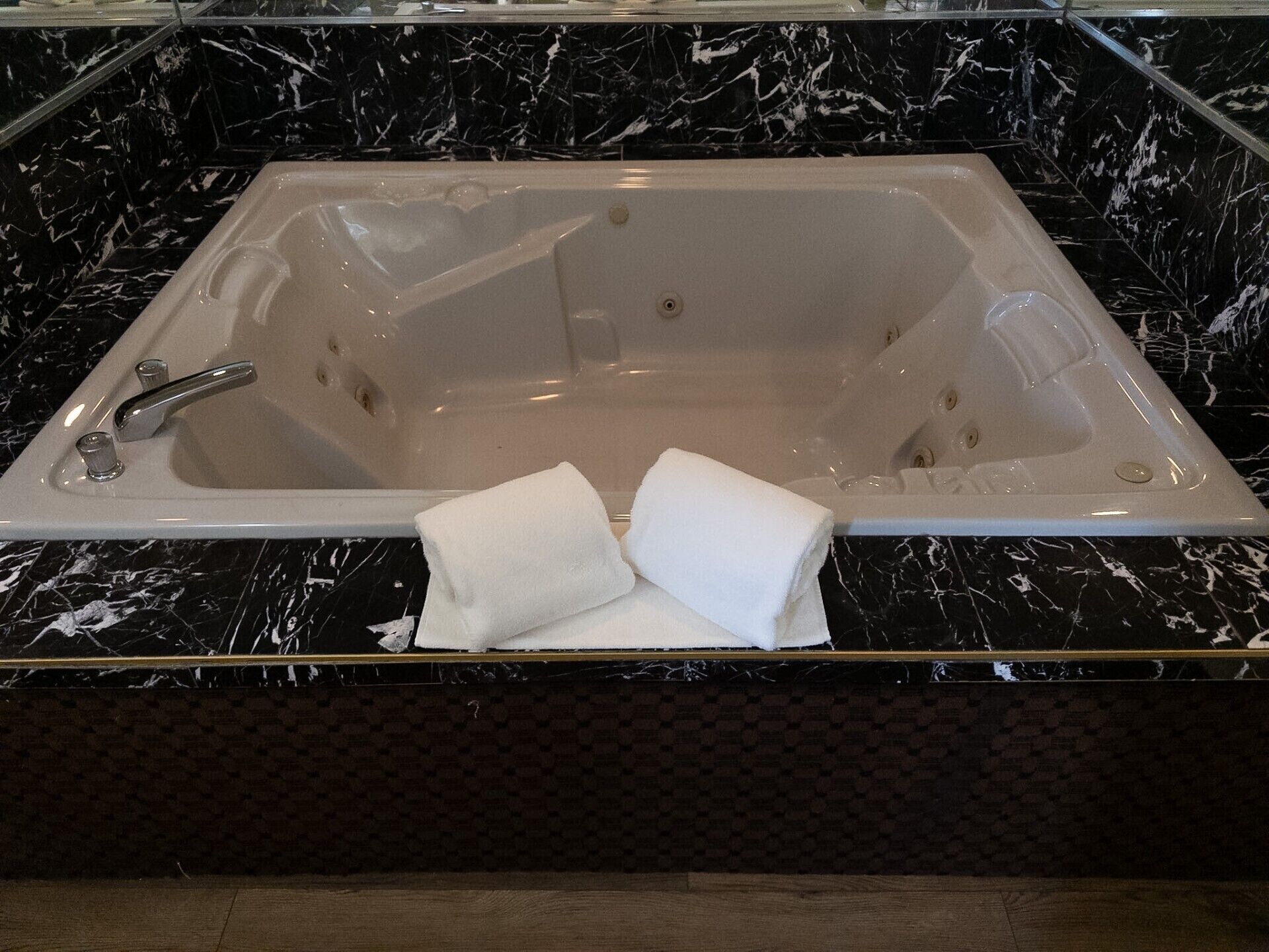 Una bañera rectangular con un solo grifo, dos toalleros con toallas blancas y una encimera de mármol.