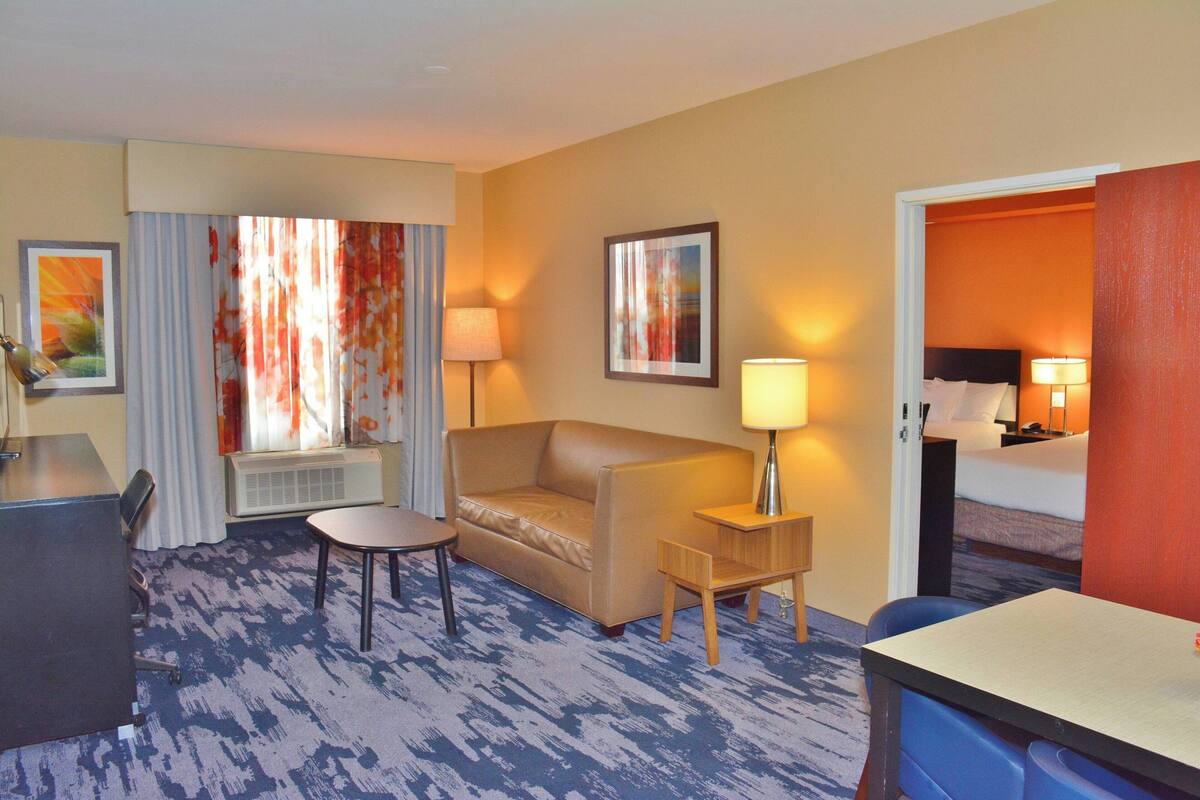 A hotel room with a sofa, a small table, a desk, and a bed.