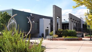 A modern building with a curved metal sculpture, a central staircase, and a landscaped courtyard with benches. - Fairfield Inn & Suites by Marriott Grand Junction Downtown (Grand Junction)