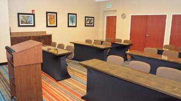 Une salle de conférence équipée d’un pupitre, de tables, de chaises et de tableaux accrochés au mur.