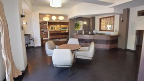 A modern hotel lobby with a reception desk, a seating area with a round table and chairs, and a visible reception counter. - Fairfield Inn & Suites by Marriott Grand Junction Downtown (Grand Junction)