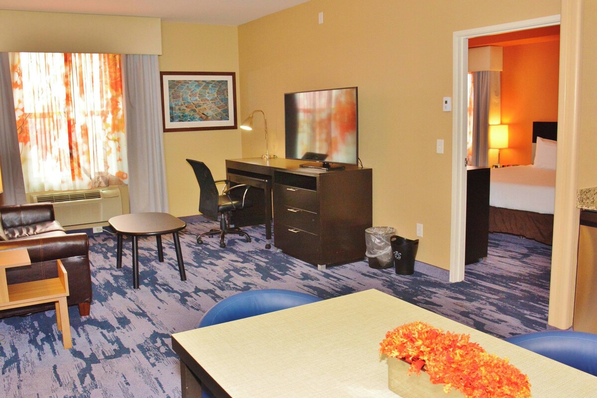 A hotel room with a desk, chair, sofa, and a bed.