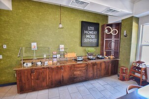 A kitchen area with a wooden counter, a sign that reads "LESS MONDAY MORE SUMMER," and a small stool.