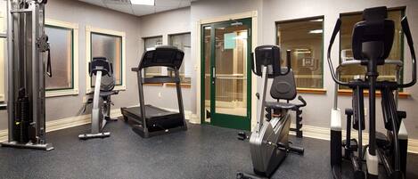 Ein Fitnessstudio mit Cardiogeräten, Krafttrainingsgeräten und einer Spiegelwand.