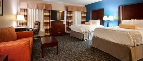 A hotel room with two beds, a desk, a chair, and a sofa.