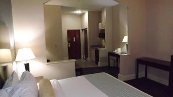 Habitación de hotel con cama, escritorio, silla, lámpara y espejo.