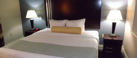 A neatly made bed with a headboard, two bedside tables with lamps, and a patterned carpet.