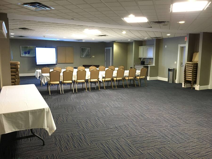 A conference room with a long table and chairs, carpeted floor, and a projector screen.