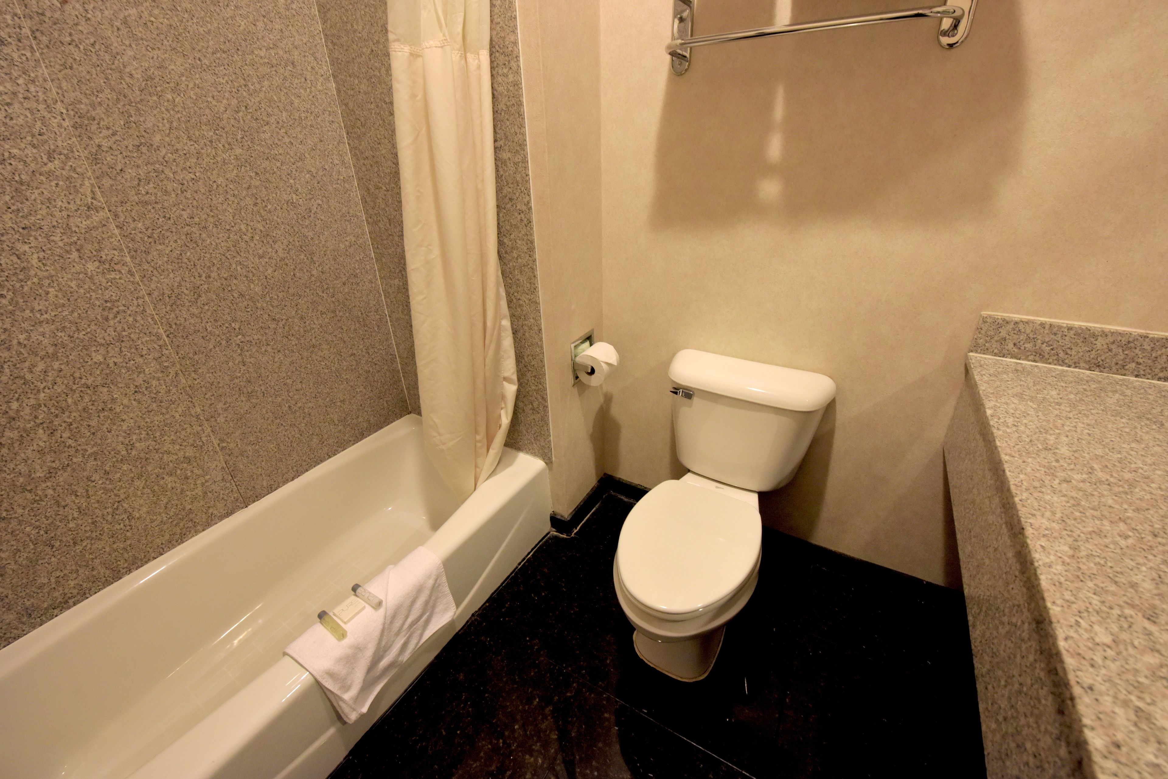 A bathroom with a bathtub, toilet, and a towel rack.