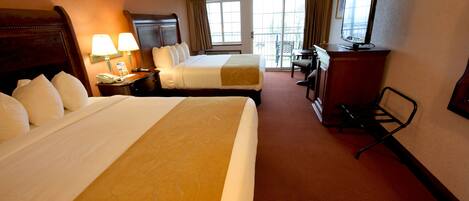 Een hotelkamer met twee bedden, een bureau, een televisie en een balkon met uitzicht.